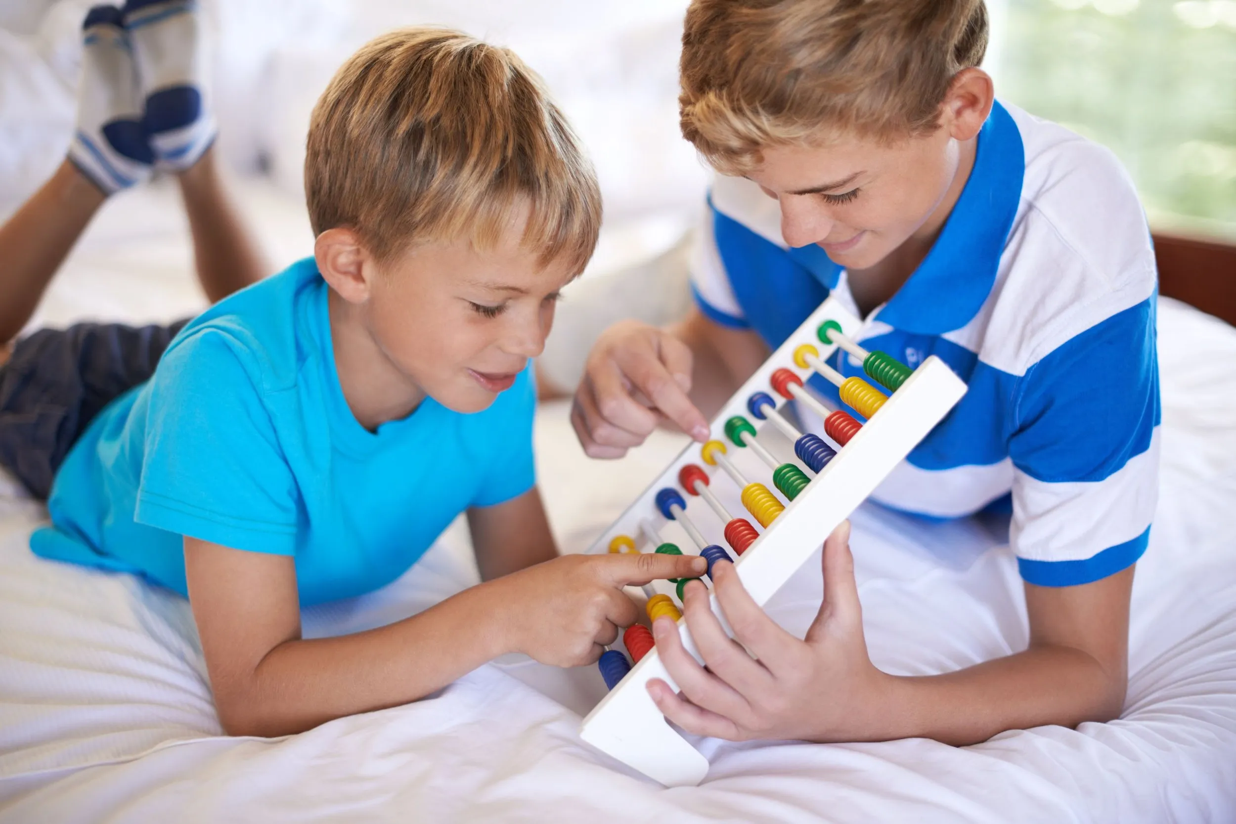 Two young boys counting colorful beads together on an abacus
