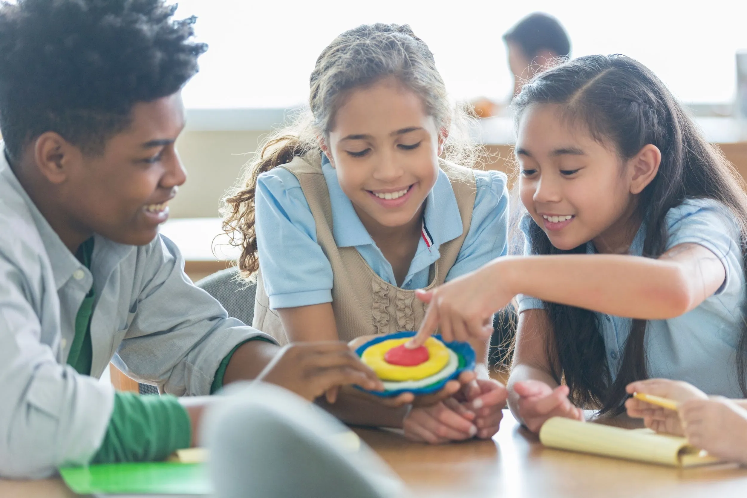 Three students collaborating on a hands-on activity at a classroom table